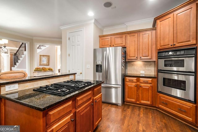 kitchen featuring ornamental molding, dark stone counters, a kitchen island, dark hardwood / wood-style flooring, and appliances with stainless steel finishes