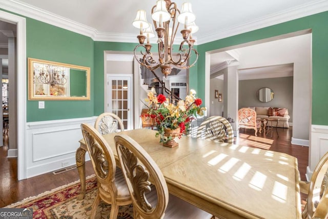 dining area with dark wood-type flooring, a notable chandelier, and crown molding