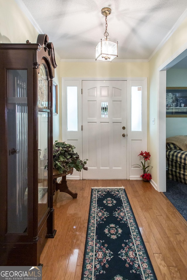 entrance foyer featuring a textured ceiling, crown molding, and hardwood / wood-style flooring