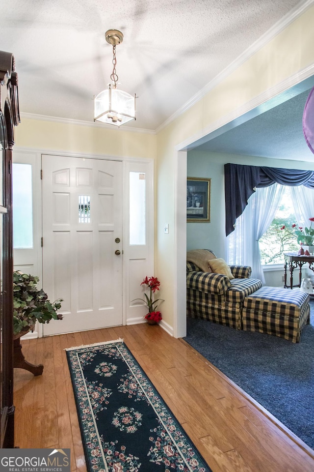 entryway with a textured ceiling, hardwood / wood-style flooring, and crown molding