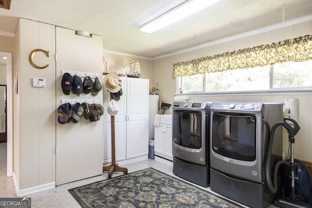 washroom featuring washing machine and clothes dryer, crown molding, a textured ceiling, and cabinets