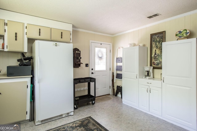 kitchen with white refrigerator, ornamental molding, and a textured ceiling