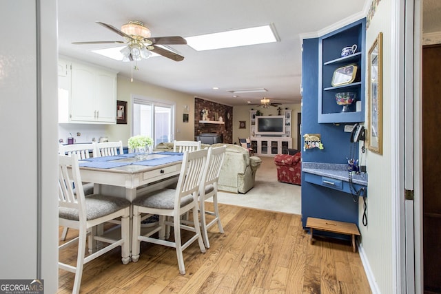 dining room featuring a brick fireplace, ceiling fan, and light hardwood / wood-style floors