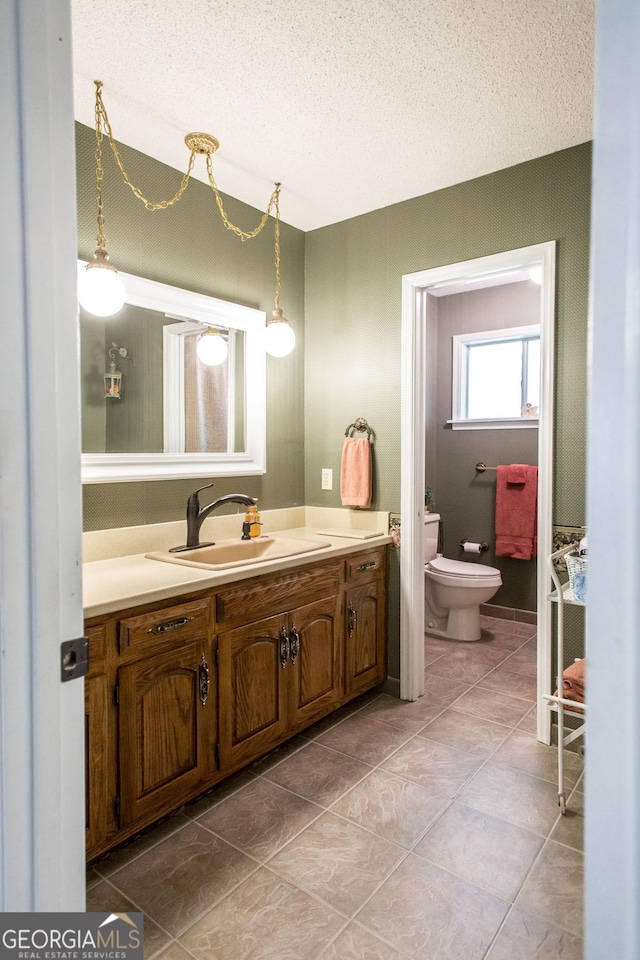 bathroom featuring a textured ceiling, tile patterned flooring, vanity, and toilet