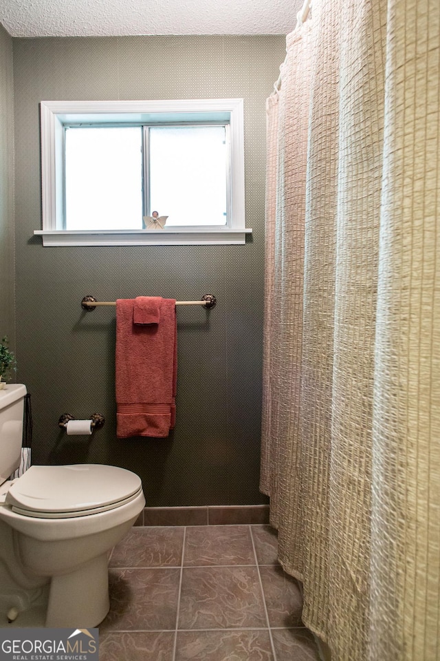 bathroom featuring a shower with shower curtain, tile patterned floors, and toilet