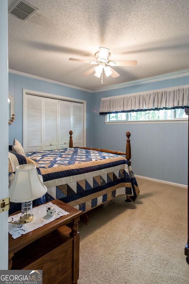 bedroom with a textured ceiling, a closet, carpet floors, ceiling fan, and ornamental molding