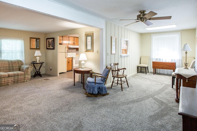 sitting room with light colored carpet, ceiling fan, and a textured ceiling