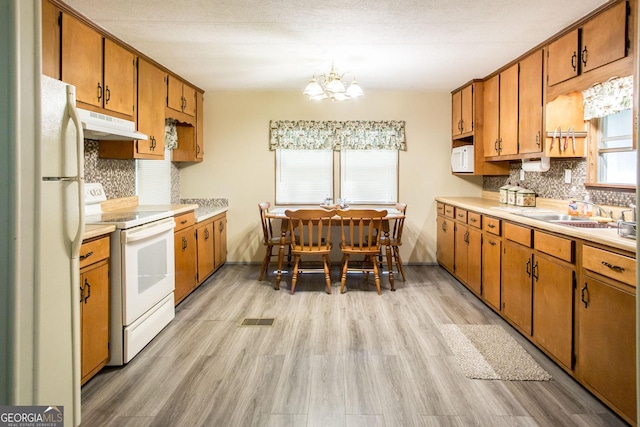 kitchen featuring sink, an inviting chandelier, white appliances, tasteful backsplash, and light hardwood / wood-style flooring