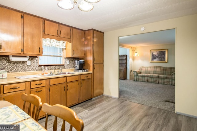 kitchen with sink, light wood-type flooring, and decorative backsplash