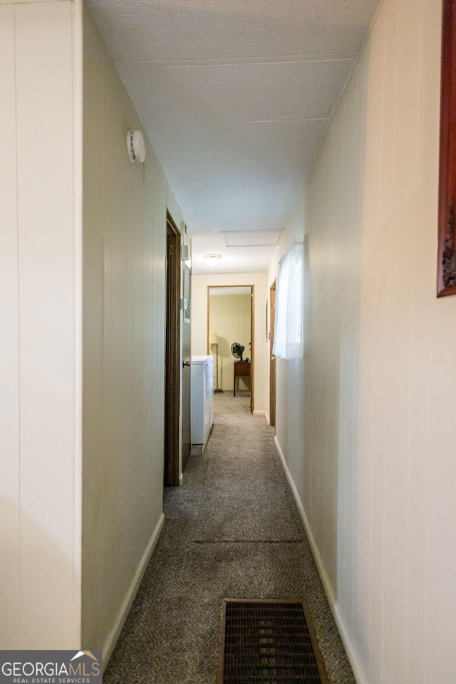 corridor featuring carpet floors, wooden walls, and separate washer and dryer