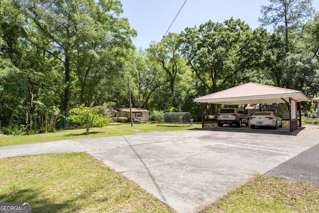 view of parking / parking lot with a carport and a lawn