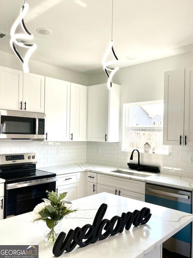 kitchen featuring appliances with stainless steel finishes, pendant lighting, and white cabinetry