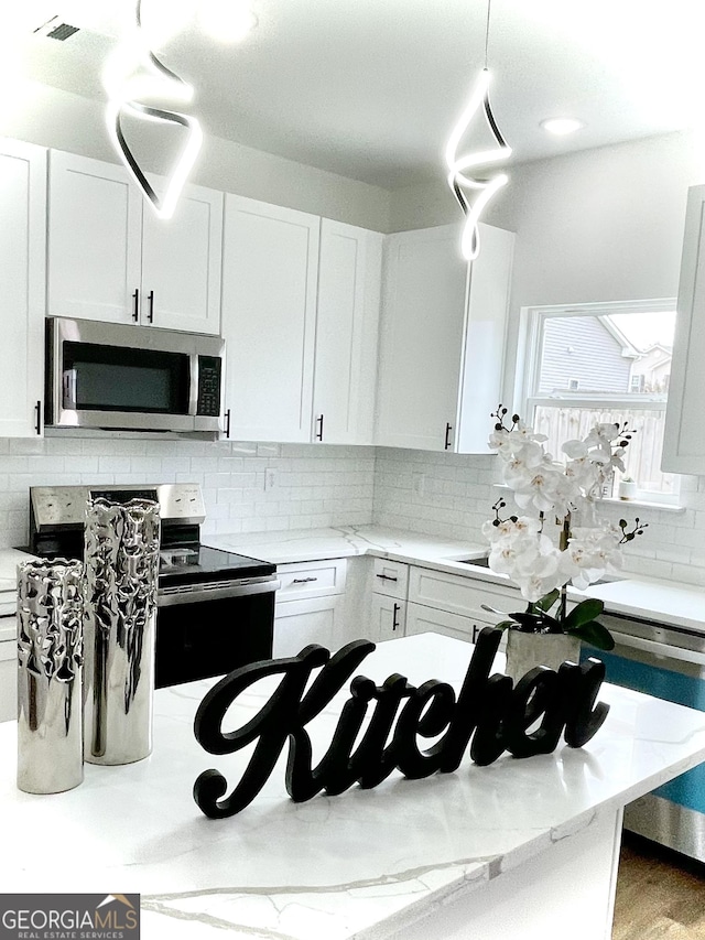 kitchen featuring stainless steel appliances, white cabinets, and tasteful backsplash