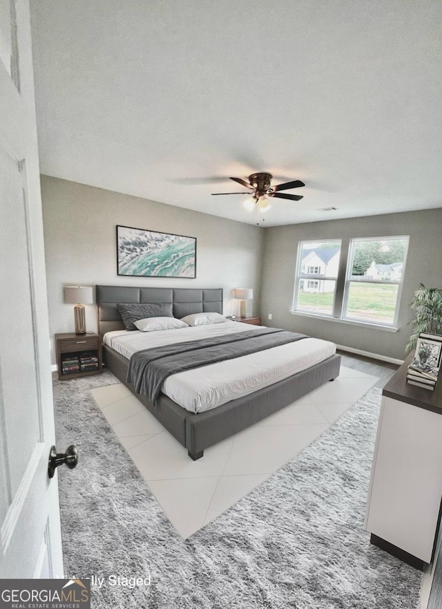 bedroom featuring a textured ceiling, ceiling fan, and light tile patterned floors