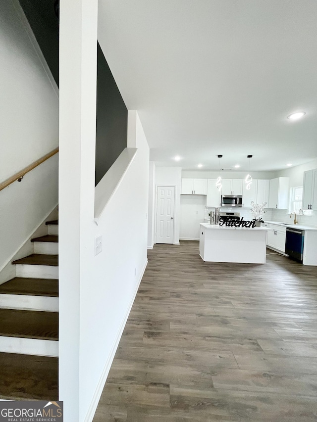 kitchen featuring hardwood / wood-style flooring, pendant lighting, a kitchen island, white cabinetry, and sink