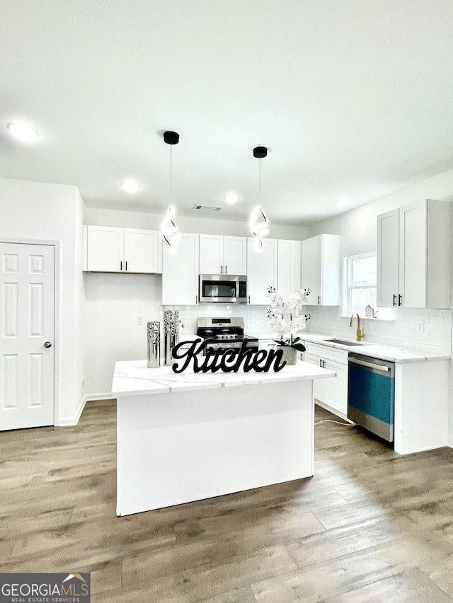 kitchen with white cabinets, stainless steel appliances, and decorative light fixtures