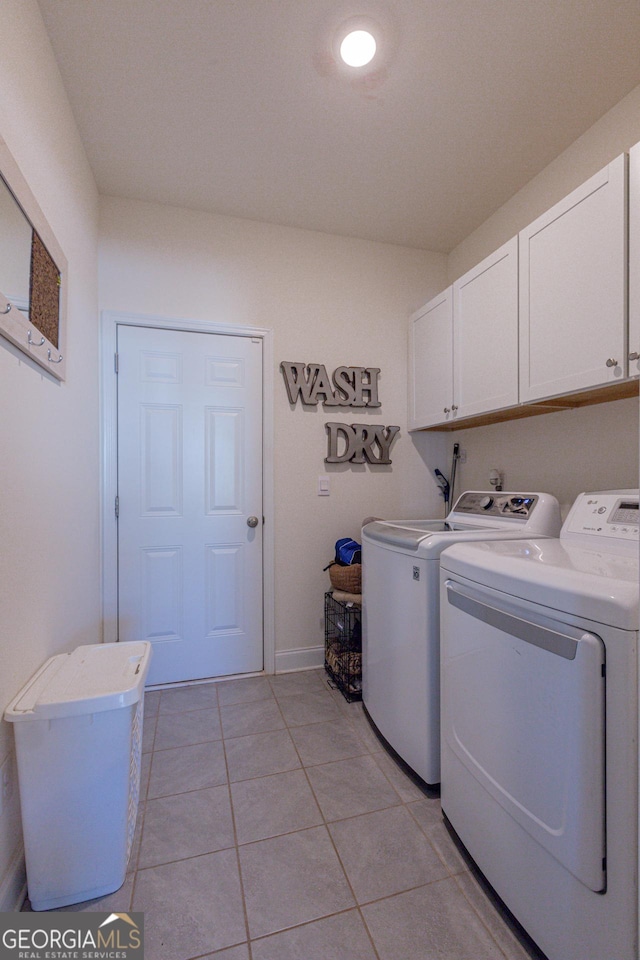 laundry room with washer and dryer, light tile patterned floors, and cabinets