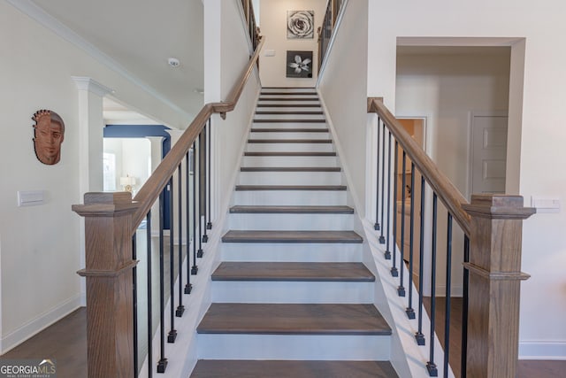 stairway with hardwood / wood-style floors, crown molding, and ornate columns