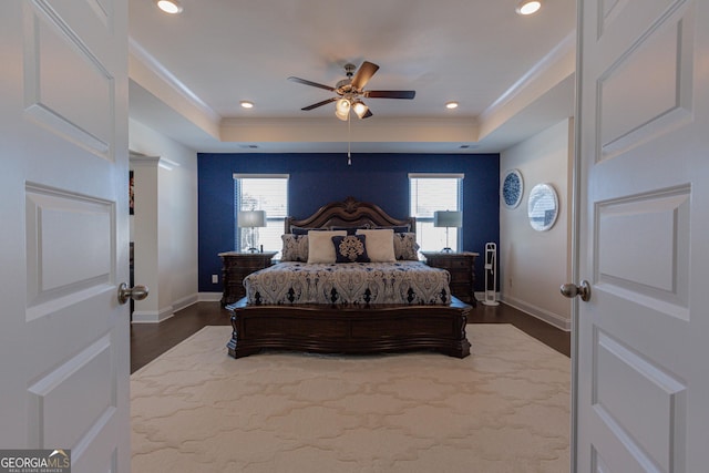 bedroom with ceiling fan, a raised ceiling, and dark hardwood / wood-style floors