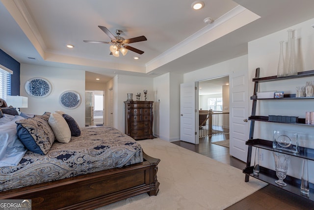 bedroom with ceiling fan, multiple windows, a raised ceiling, and wood-type flooring