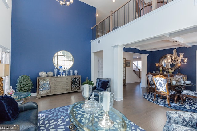 living room featuring an inviting chandelier, decorative columns, beamed ceiling, hardwood / wood-style flooring, and coffered ceiling