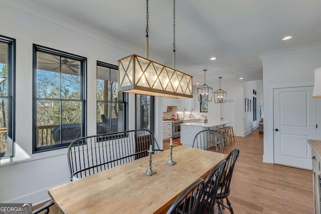 dining area with light wood-type flooring and ornamental molding