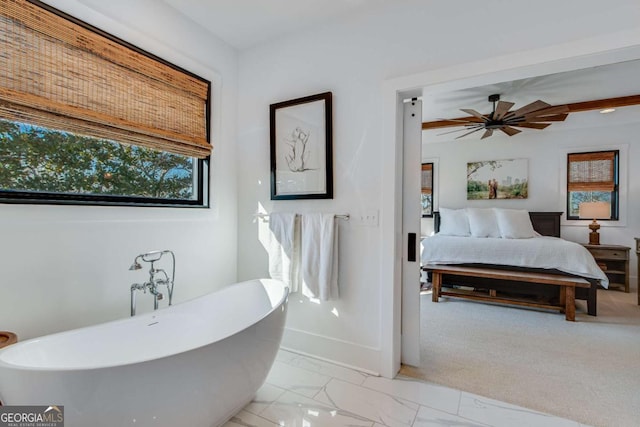 bathroom with beam ceiling, ceiling fan, and a tub to relax in