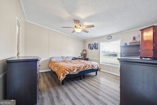 bedroom with ornamental molding, a textured ceiling, ceiling fan, and dark hardwood / wood-style flooring