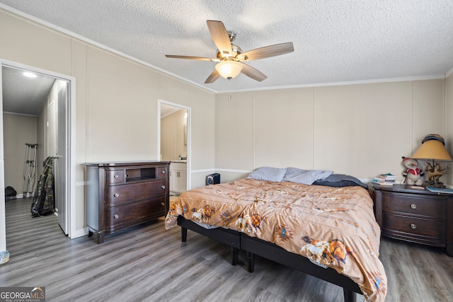 bedroom featuring ceiling fan, ensuite bath, a textured ceiling, and wood-type flooring