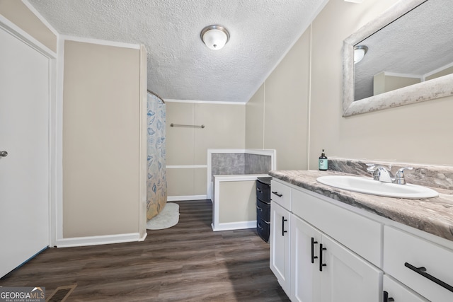 bathroom featuring a textured ceiling, walk in shower, crown molding, wood-type flooring, and vanity