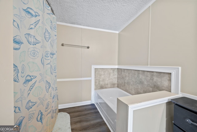 bathroom featuring a textured ceiling, hardwood / wood-style floors, a bathtub, and crown molding