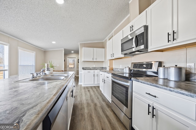 kitchen featuring wood-type flooring, white cabinets, crown molding, and appliances with stainless steel finishes