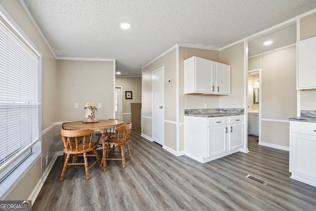 kitchen with white cabinetry, light wood-type flooring, a textured ceiling, and crown molding