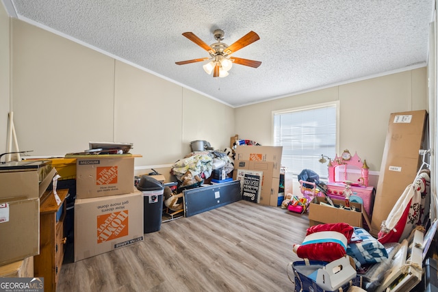 playroom with ceiling fan, a textured ceiling, ornamental molding, and hardwood / wood-style flooring