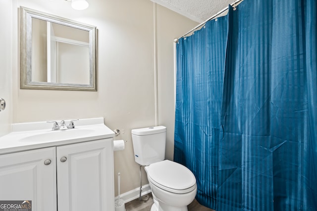 bathroom featuring toilet, a textured ceiling, walk in shower, and vanity