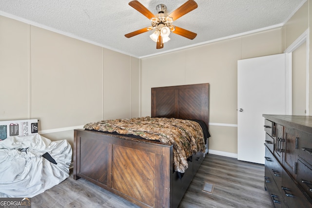 bedroom featuring ceiling fan, crown molding, a textured ceiling, and dark hardwood / wood-style floors