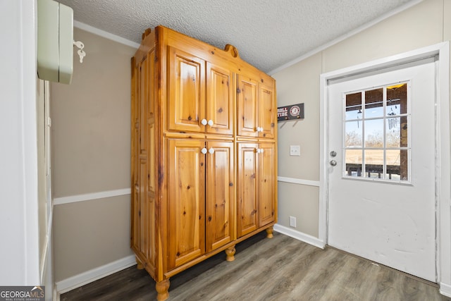 entryway featuring a textured ceiling, dark wood-type flooring, and ornamental molding