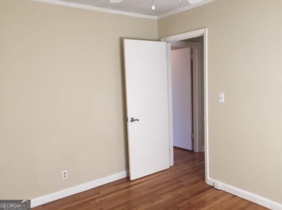 spare room with ornamental molding, dark wood-type flooring, and ceiling fan