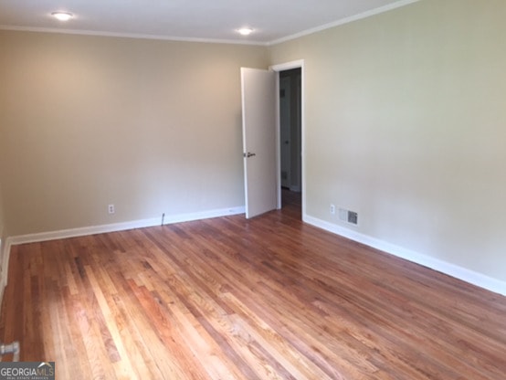 empty room with ornamental molding and hardwood / wood-style flooring