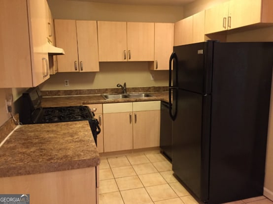 kitchen with sink, light brown cabinets, black appliances, and light tile patterned floors