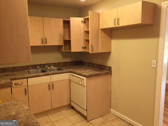 kitchen featuring sink, white dishwasher, light brown cabinetry, and light tile patterned floors