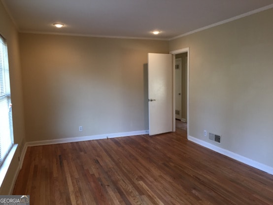 spare room featuring crown molding, a wealth of natural light, and dark hardwood / wood-style floors