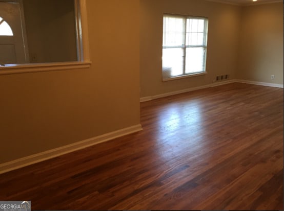 empty room featuring dark hardwood / wood-style flooring and ornamental molding