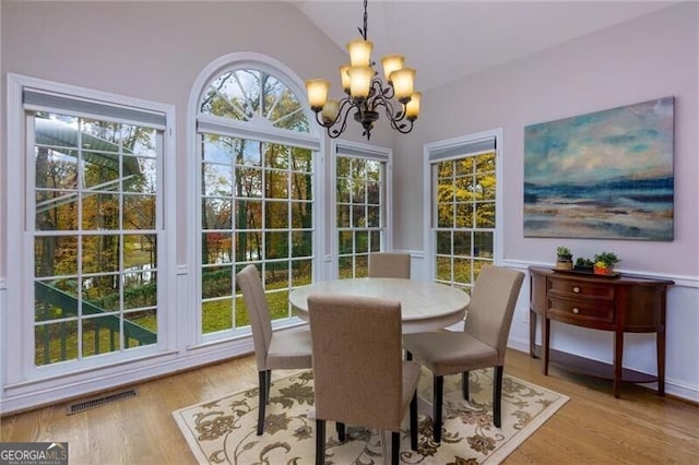 dining room featuring light wood-type flooring, an inviting chandelier, and vaulted ceiling