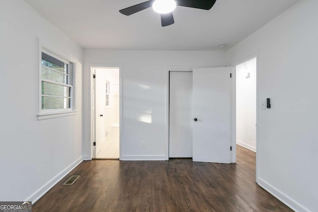 unfurnished bedroom featuring ensuite bathroom, dark hardwood / wood-style flooring, a closet, and ceiling fan