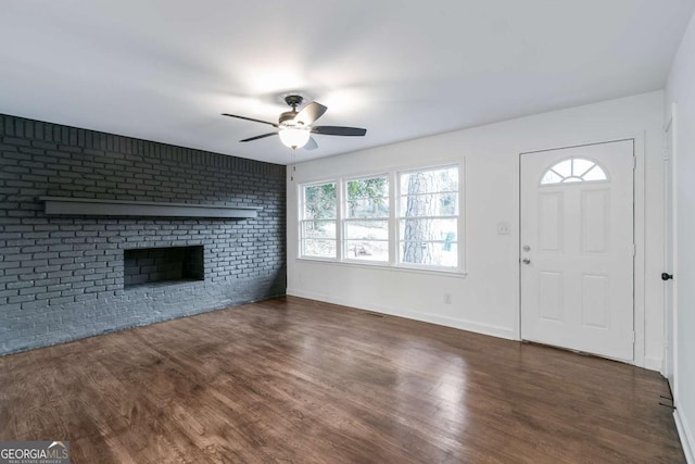 unfurnished living room featuring ceiling fan, dark hardwood / wood-style flooring, a fireplace, and brick wall