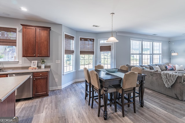 dining area with ornamental molding and light hardwood / wood-style floors