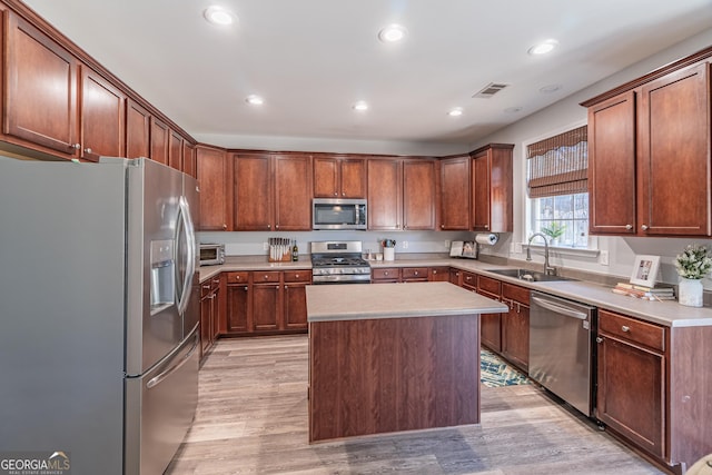 kitchen with sink, a center island, stainless steel appliances, and light wood-type flooring