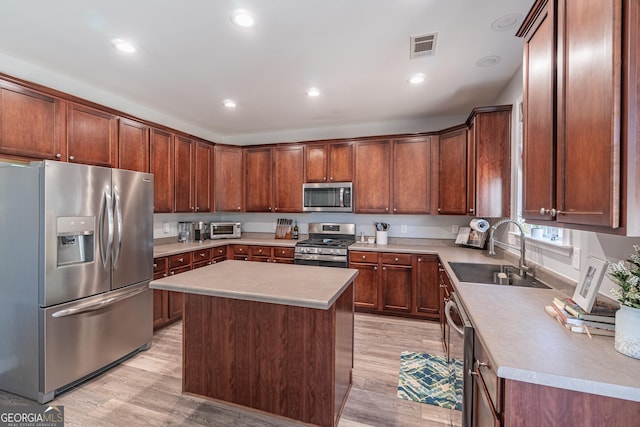 kitchen with sink, a center island, stainless steel appliances, and light hardwood / wood-style flooring