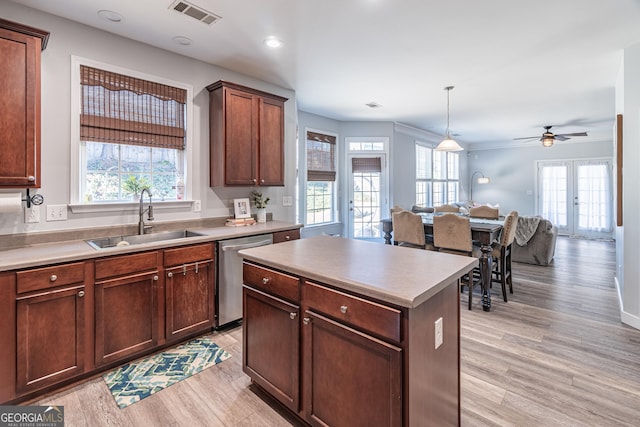 kitchen featuring pendant lighting, a center island, light hardwood / wood-style floors, sink, and stainless steel dishwasher